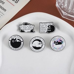 Set aus minimalistischen schwarz-weißen Emaille-Katzenpins mit lustigen Sprüchen auf Tablett