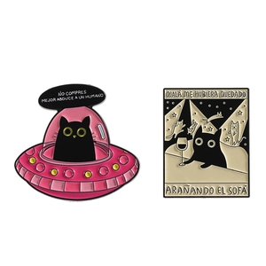 Set of two black cat enamel pins featuring a pink UFO and a cozy night scene with slogans
