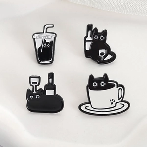 Close-up of four black cat enamel pins in wine and coffee cup designs with metal finish
