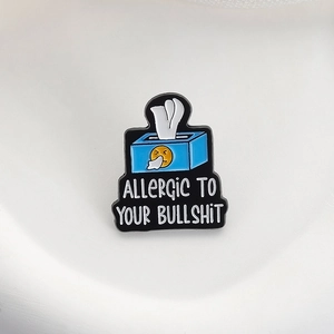 Detailed view of enamel pin featuring blue tissue box and Allergic To Your Bullshit text