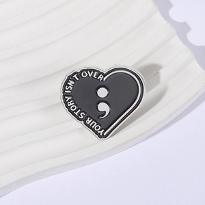 Black heart enamel pin with semicolon and Your Story Isn't Over inspirational text