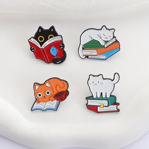 Set of four cute cartoon cat and book enamel pins displayed on a white tray