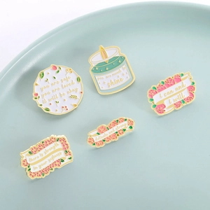 5pcs set of floral enamel pins with motivational quotes on a mint green ceramic plate