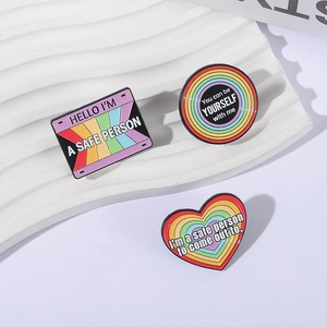 LGBTQ+ rainbow enamel pin set with safe person slogans on a white textured display