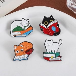Set of four cute cartoon cat enamel pins featuring sleeping and reading cats on books