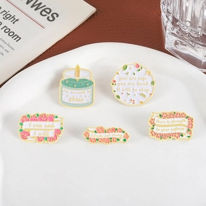 5-piece floral enamel pin set with motivational quotes in a white ceramic dish