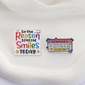 Broches émaillées colorées Be the Reason Someone Smiles sur un plateau en céramique blanc
