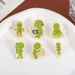 Set of 6 green funny enamel pins with weirdcore designs and humorous sayings on a ceramic plate