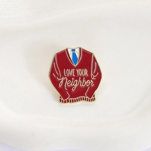 Love Your Neighbor enamel brooch pin featuring a red sweater design with golden edges
