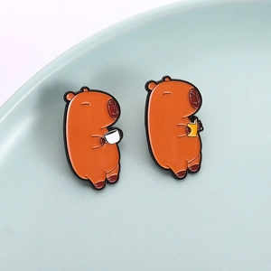 Set of two cute capybara enamel pins featuring coffee and book designs for backpacks