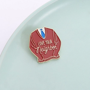 Red sweater enamel pin with Love Your Neighbor text and blue tie detail on mint tray