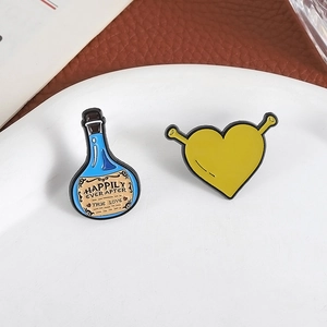 Mini enamel pins featuring blue magic potion bottle and yellow heart with Shrek ears