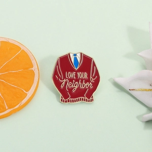 Classic red sweater enamel pin with Love Your Neighbor quote and blue tie design