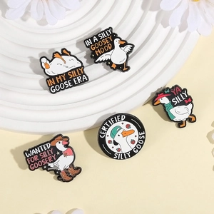 Set of five white cartoon goose enamel pins with funny quotes on a white tiered display