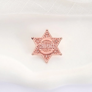 Macro detail of rose gold hexagonal star sheriff badge with intricate engraved patterns