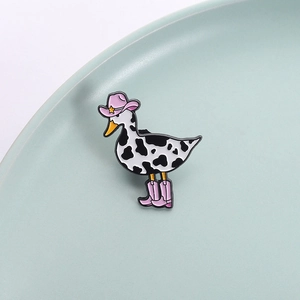Cool cowboy duck enamel pin with cow print patterns and pink boots in a ceramic bowl