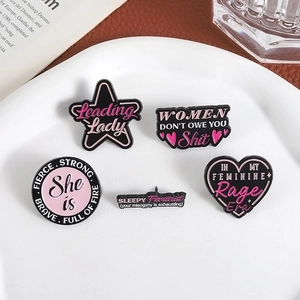 Five-piece feminist enamel pins set with pink hearts and stars on a white display plate