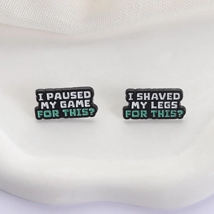 Set of two humorous enamel pins featuring funny gaming and grooming phrases on white ceramic
