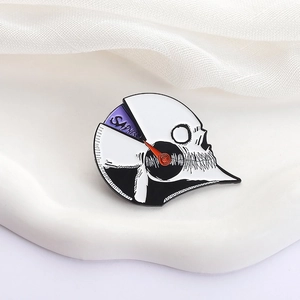 Détail du pin's crâne en émail avec cadran SADNESS sur un support blanc texturé