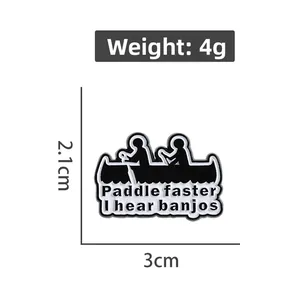 Detail showing enamel brooch size 3cm by 2.1cm with Paddle Faster I Hear Banjos text