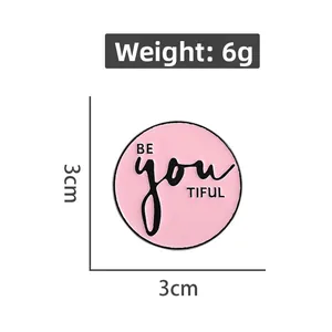 Détail du badge émaillé rose Be You Tiful de 3cm avec indications de poids et taille