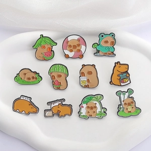 Enamel capybara pins set featuring watermelon and frog leaf motifs on a ceramic tray