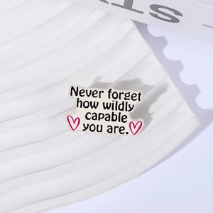 Pin's inspirant en émail blanc avec texte et cœurs roses sur un fond décoratif Paris