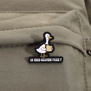 Funny cartoon duck enamel pin with Is This Gluten Free text on a khaki canvas bag