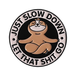 Round enamel sloth pin with Just Slow Down text on a white minimalist background