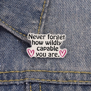 Vue détaillée du pin's émaillé inspirant sur denim montrant la citation motivante
