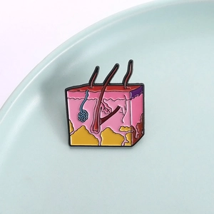 Enamel brooch with human skin anatomy design showing layers and hair follicles