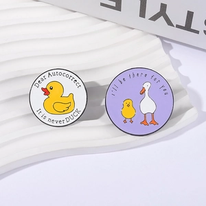 Cartoon animal enamel pins with cute duck and goose designs on a white artistic stand