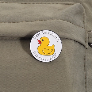 Close-up of a round enamel duck pin with a funny quote on khaki nylon fabric texture