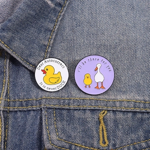 Detail of funny enamel duck pins on blue denim jacket with creative English slogans