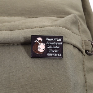 Detail of cartoon bird enamel pin with German beer text pinned on a backpack strap
