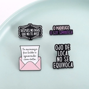 Set of four unique enamel pins with Spanish quotes on a minimalist teal tray
