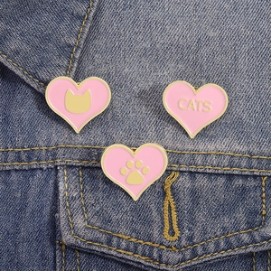 Broches en émail rose en forme de cœur avec bordure dorée sur un tissu en jean bleu