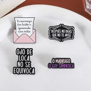 Set of four creative enamel pins with positive Spanish quotes on white ceramic plate