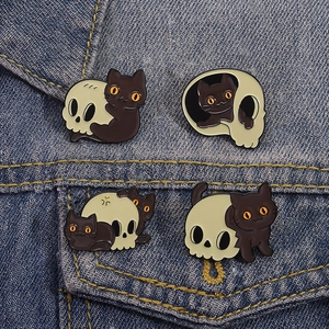 Detail of four dark cat and skull enamel pins set on a blue denim jacket pocket