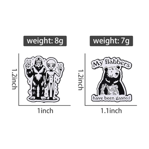 Dettaglio delle spille smaltate con alieno e orso con specifiche di peso e dimensioni