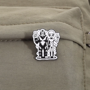 Détail du badge émaillé Bigfoot et extraterrestre sur la sangle d'un sac à dos vert