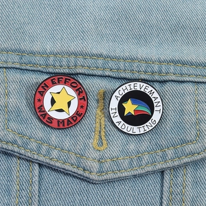 Broches en émail étoile avec texte motivant épinglées sur une veste en jean bleu clair