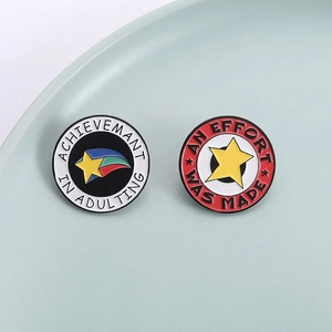 Set van twee ronde emaille speldjes met sterpatronen en humoristische slogans