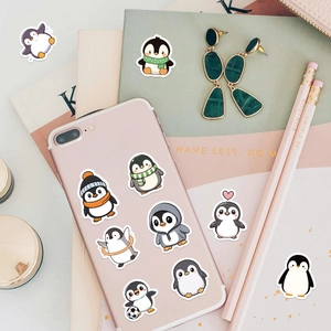 Gros plan d'autocollants pingouins mignons sur un smartphone rose et un carnet déco