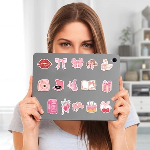 Roze cartoon stickerset met strikken en kersen op een grijze tablet in de handen