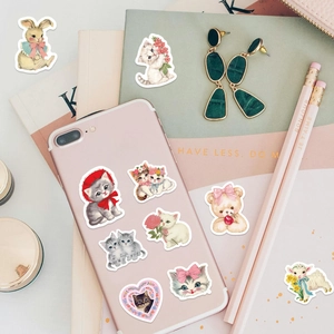 Flat lay of cute cartoon animal stickers on a pink phone and stationery set