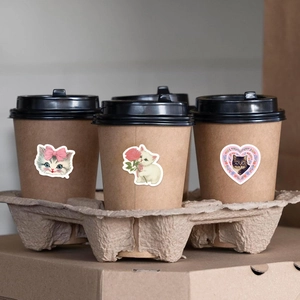 Detail showing cartoon cat stickers on a craft coffee cup with warm aesthetic tones