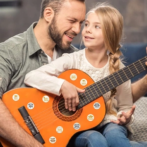 Class of 2025 graduation stickers shown decorating a guitar in a warm family setting
