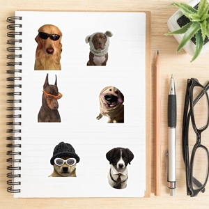 Funny dog stickers with sunglasses and hats on a white notebook over wooden background