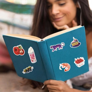 Mediterranean aesthetic stickers applied to a blue book held by a woman in a lifestyle setting